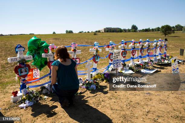 Kimber Avra sits by a cross honoring her friend Micayla Medek at a remembrance ceremony July 20, 2013 in Aurora, Colorado. The ceremony marks the one...