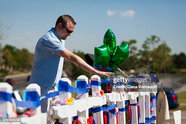 Joshua Nowlan visits the 12 crosses erected near the Aurora Municipal Building July 20, 2013 in Aurora, Colorado. A remembrance ceremony marks the...