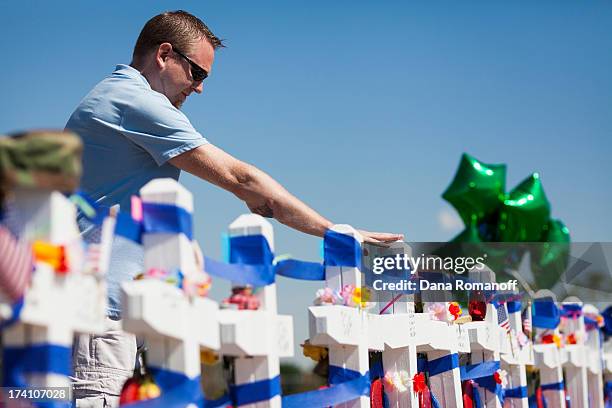 Joshua Nowlan visits the 12 crosses erected near the Aurora Municipal Building July 20, 2013 in Aurora, Colorado. A remembrance ceremony marks the...