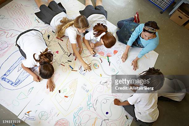 children working on a large drawing together - schoolboy foto e immagini stock