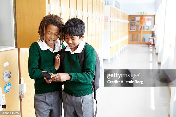 boys playing on a cell phone at school - cell phones in school stock pictures, royalty-free photos & images