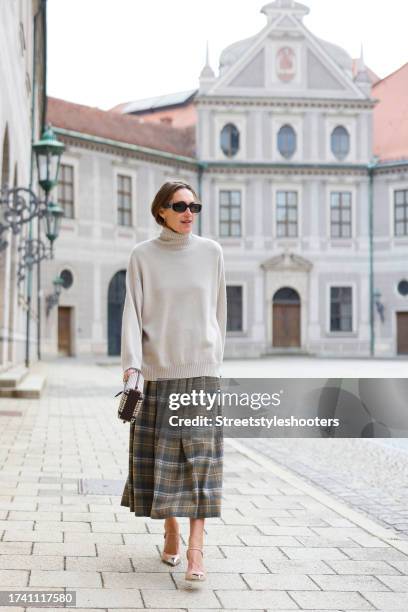 Influencer Annette Weber, wearing a green checked skirt by Loro Piana, a beige turtleneck by Brunello Cucinelli, a checked bag by Tory Burch, beige...