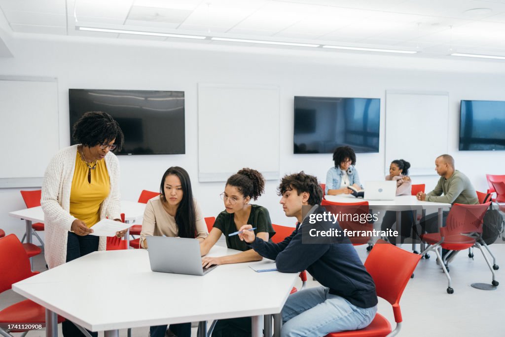 Teacher helping University Students in Classroom