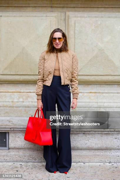 Influencer Annette Weber, wearing black pants by Max Mara, a beige bomber jacket by Max Mara, a red bag by Ferragamo, red pumps by Ferragamo and...