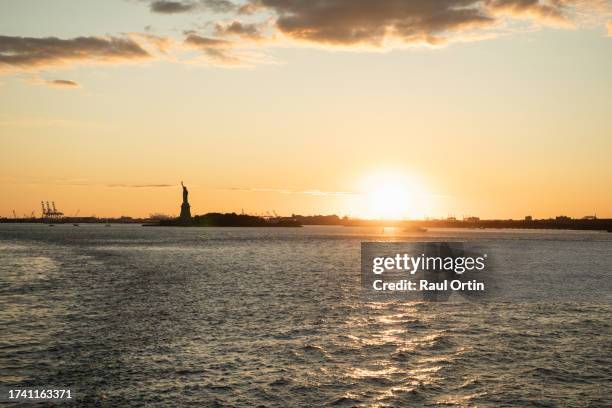 the statue of liberty at sunset in new york city . - new york liberty center stock pictures, royalty-free photos & images