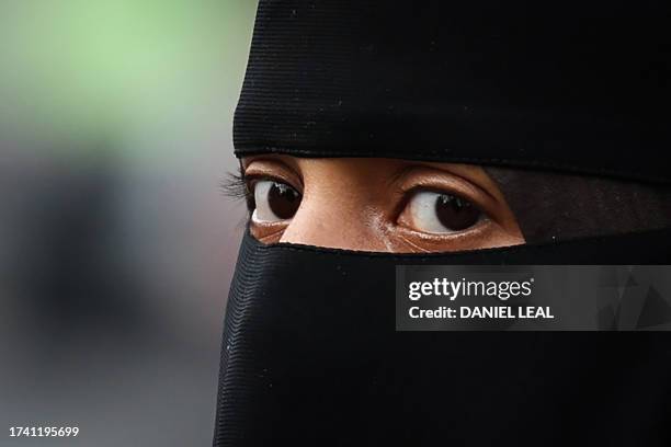 Woman wearing a niqab looks on as she walks in the streets of London, on October 23, 2023.