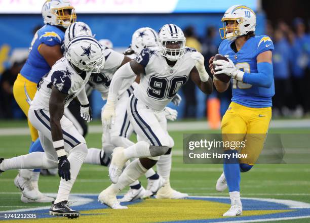 Justin Herbert of the Los Angeles Chargers scrambles away from DeMarcus Lawrence and Markquese Bell of the Dallas Cowboys during a 20-17 loss to the...