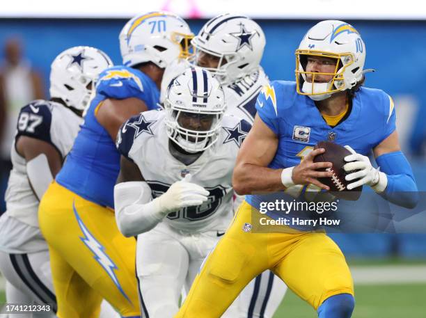 Justin Herbert of the Los Angeles Chargers scrambles from DeMarcus Lawrence of the Dallas Cowboys during a 20-17 loss at SoFi Stadium on October 16,...