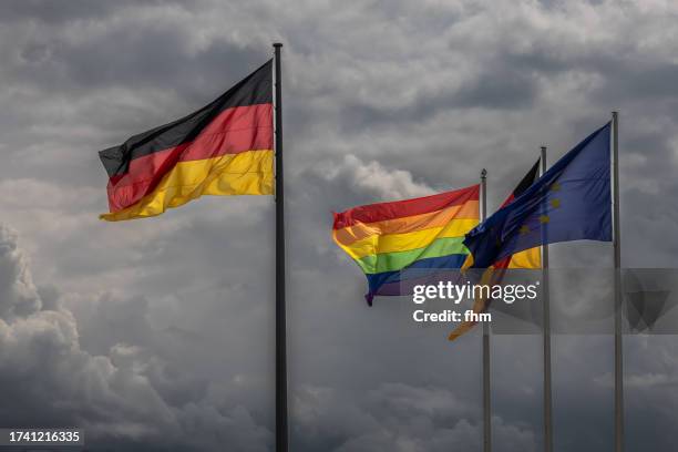 german-, eu- and rainbow(lgbt+)- flag with dramatic clouds in the sky - berlin gay pride stock pictures, royalty-free photos & images