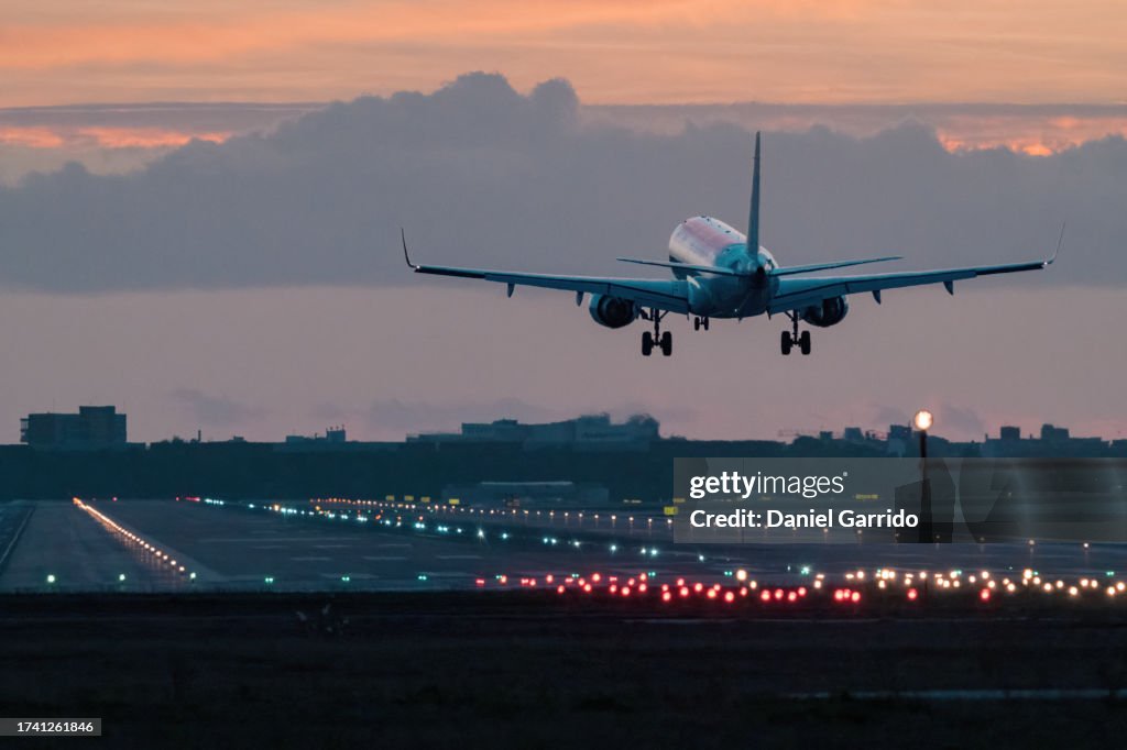 Landing in sunset hues, airplane landing at sunrise.