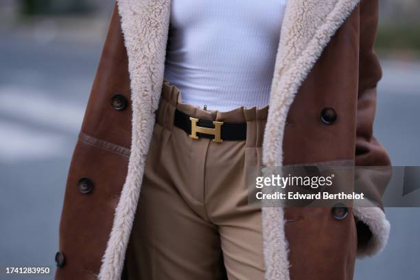 Emy Venturini wears vintage beige pants, a Hermes belt, a long brown aviator coat with sheep wool inner lining from Eleh, during a street style...