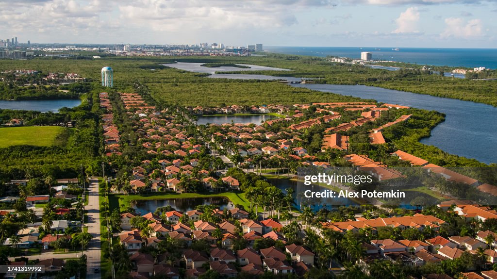 Coastal living by the Atlantic Ocean in Hollywood, Florida: detached houses overlooking the marina in Florida. Water tower and Fort Lauderdale skyscrapers visible in the distance. Aerial view