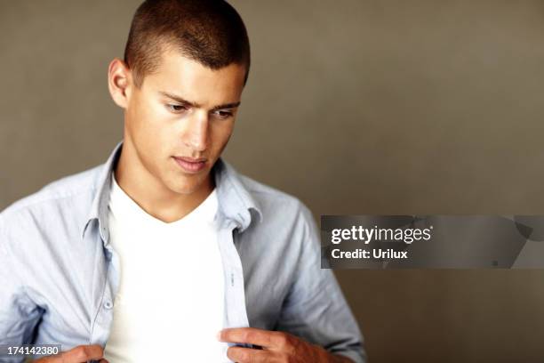 smart young man buttoning his shirt on grunge background - buttoning shirt stockfoto's en -beelden