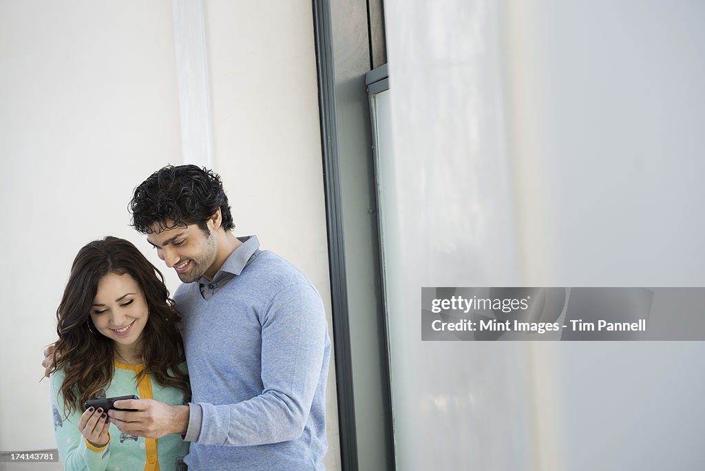 Urban Lifestyle. A young couple, man and woman side by side, looking at a mobile phone. 