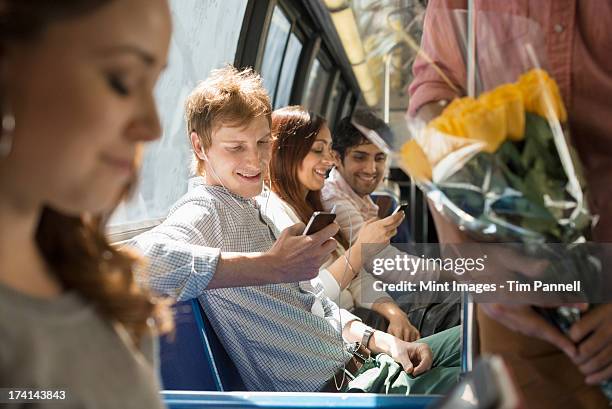 urban lifestyle. a group of people, men and women on a city bus, in new york city. two people checking their smart phones. - two men one woman fotografías e imágenes de stock