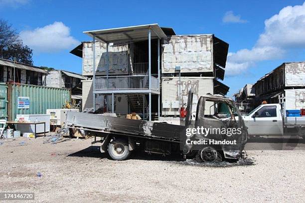 In this handout photo provided by the Australian Department of Immigration, Destroyed vehicles and accommodation are seen after rioters caused...