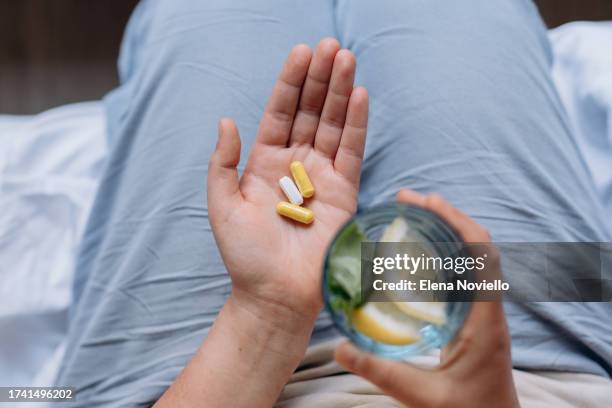 woman taking her vitamins and supplements, variety of pills and capsules in hands - hand holding several pills photos et images de collection