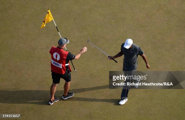 Tiger Woods of the United States hands his putter to caddie Joe LaCava on the 17th green during the third round of the 142nd Open Championship at...