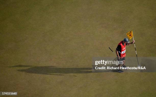 Tiger Woods of the United States' caddie Joe LaCava replaces the pin on the 17th green during the third round of the 142nd Open Championship at...