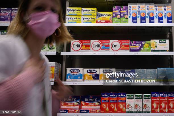 Pharmaceutical assistant passes by a shelf in a pharmacy in Riedisheim, eastern France on October 23, 2023. Health authorities warn about risks of...