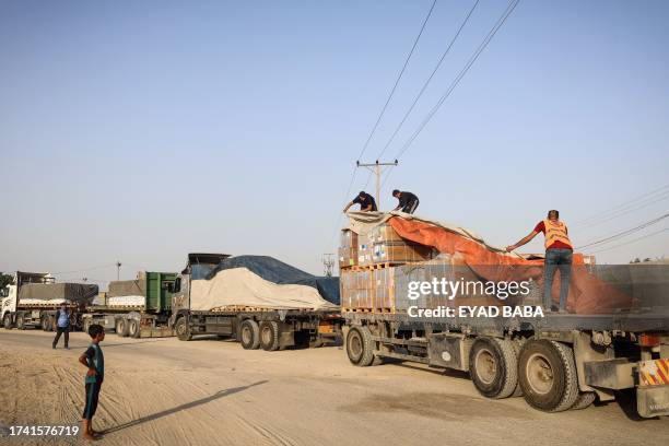 People unload humanitarian aid on a convoy of lorries entering the Gaza Strip from Egypt via the Rafah border crossing on October 21, 2023. The...