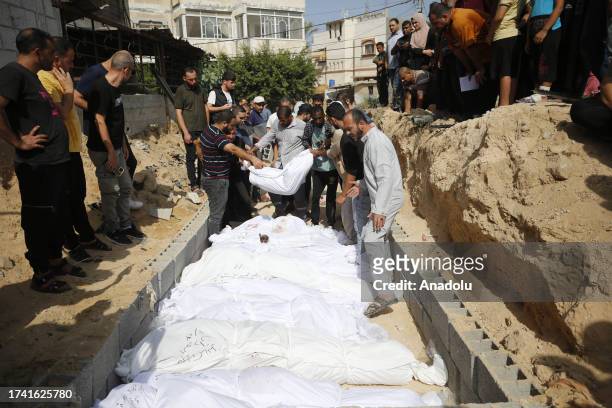 People bury bodies of killed Palestinians in the mass grave, prepared in the city cemetery since there is no empty space in some cemeteries due to...