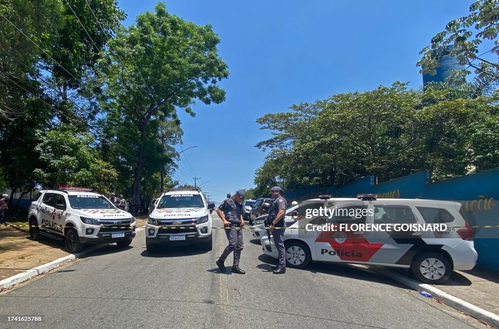 Police officers close the road outside the Sapopemba public school