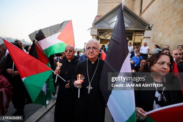 Palestinian christians wave national flags during a demonstration in solidarity with the people of Gaza in the village of Jifna, north of Ramallah in...