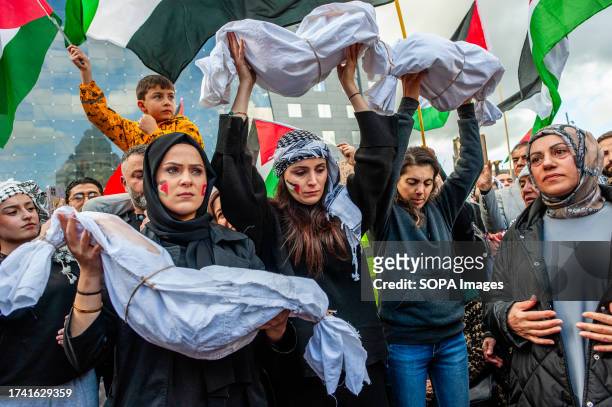 Protesters seen holding simulating dead baby bodies during the demonstration. Palestinians and their supporters keep protesting to condemn the...