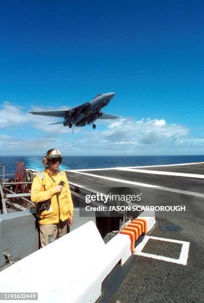 This image released 22 September 2001 by the US Navy shows an Arresting Gear Officer evaluating conditions on the flight deck as an F-14 "Tomcat"...