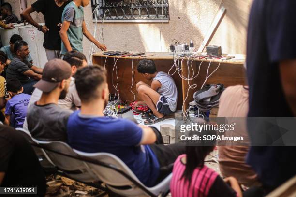 Palestinian boy sits under the table inside the Al-Amal Hospital of the Palestinian Red Crescent Society to charge his mobile phone following the...