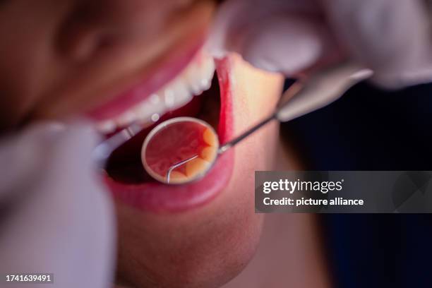 October 2023, North Rhine-Westphalia, Mönchengladbach: Dentist Dr. Kranz uses a mirror to look at a patient's teeth in his dental practice. Photo:...