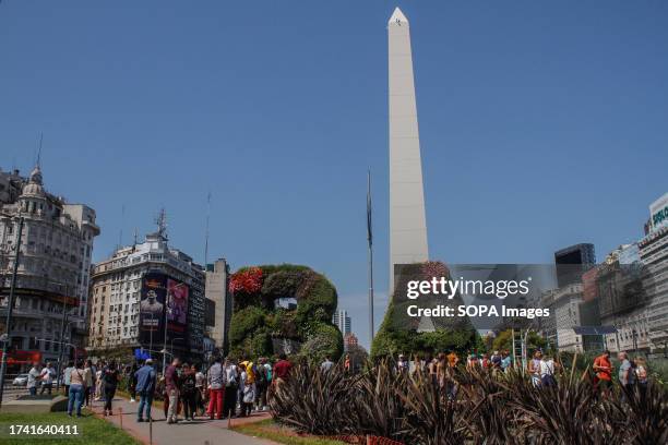 People walk by the Obelisk of Buenos Aires, a historical monument, considered an icon of Buenos Aires.