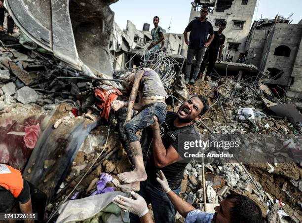 People carry a dead body of a girl pulled from rubble as civil defense teams and residents conduct a search and rescue operation for Palestinians...
