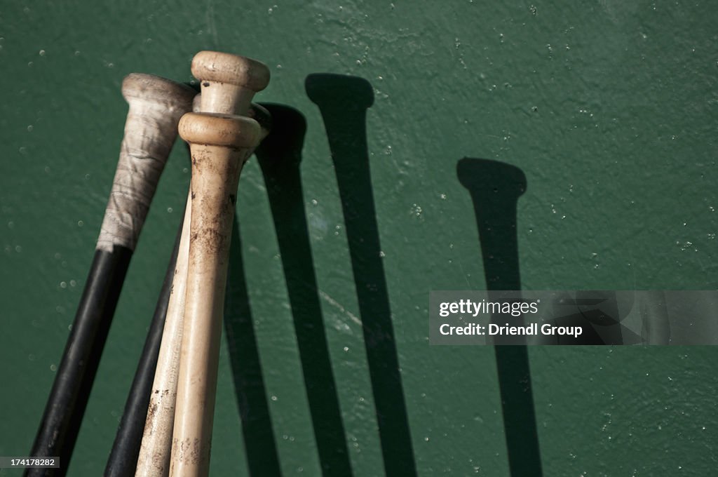 Baseball bats making shadows on dugout wall.