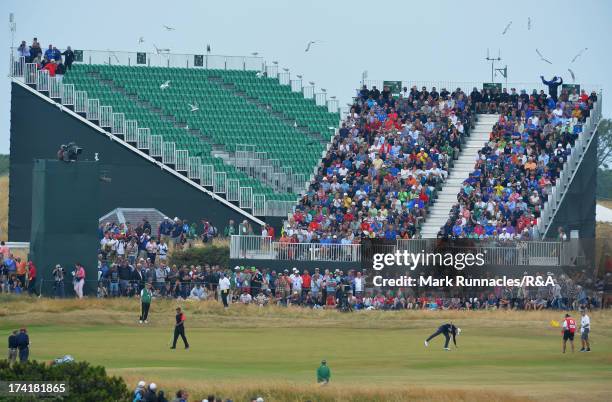 Tiger Woods of the United States wals across a green as Adam Scott of Australia marks his ball during the final round of the 142nd Open Championship...