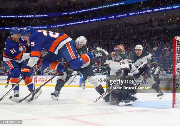 Brock Nelson of the New York Islanders is tripped up by Karel Vejmelka of the Arizona Coyotes during the third period at UBS Arena on October 17,...