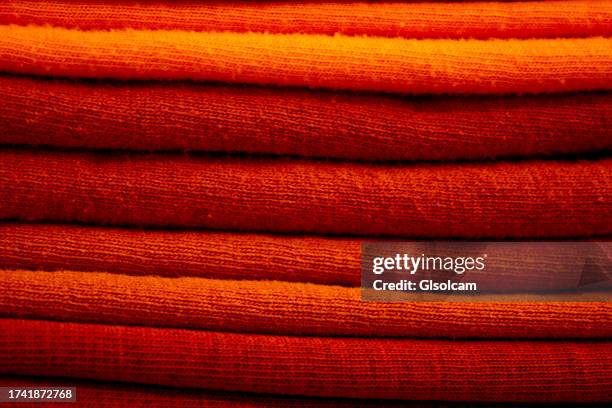 organized pile of orange shirts close-up - orange dress stock pictures, royalty-free photos & images