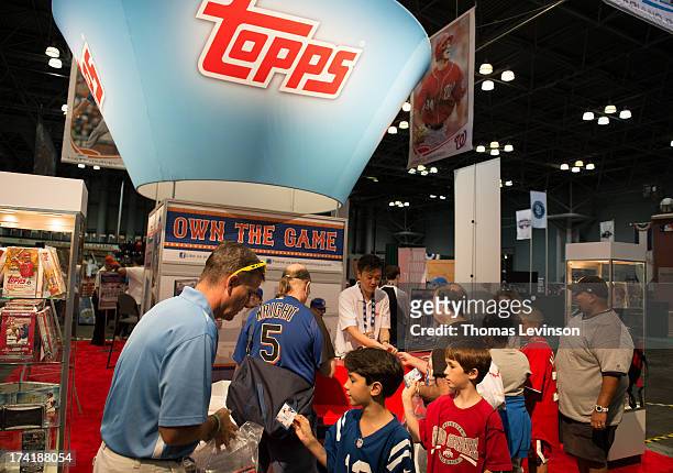Attendees open packs of trading cards at the Topps booth during the Opening Day of T-Mobile All-Star FanFest at the Jacob K. Javits Convention Center...