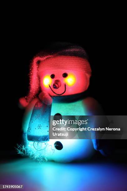 snowman with santa claus hat,hand warmer gloves and neck gaiter (8) with red and blue led light in black background - buff stock pictures, royalty-free photos & images