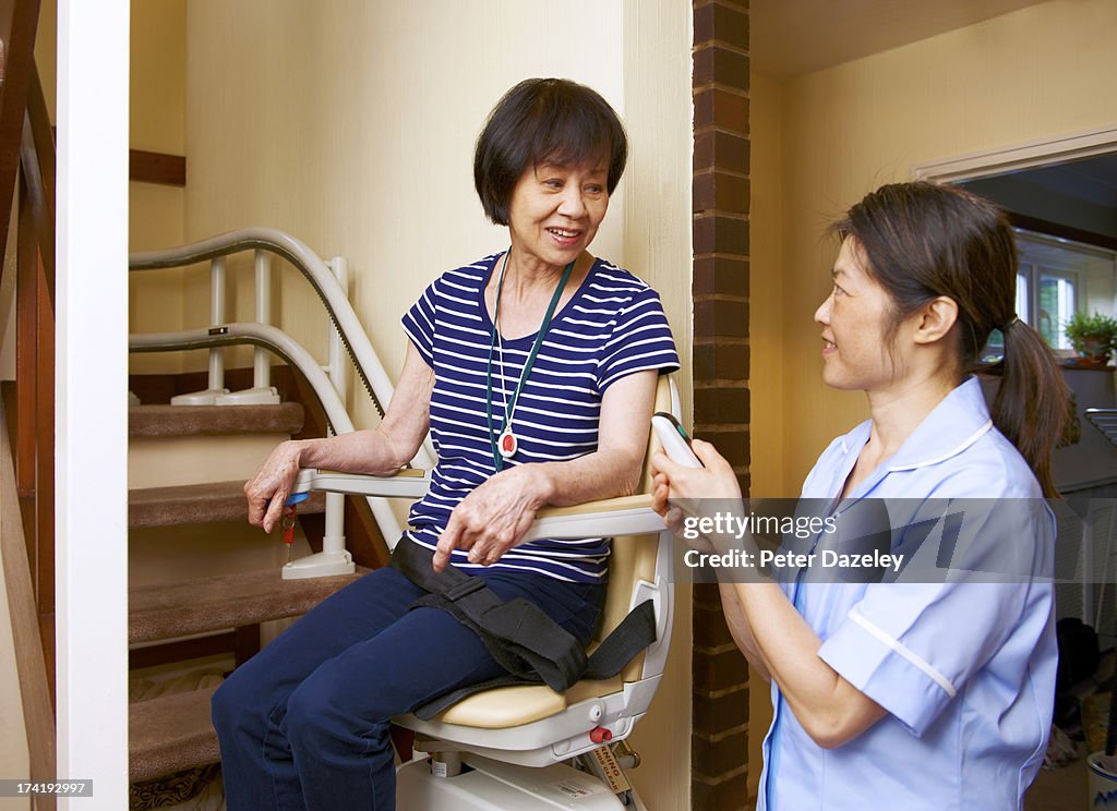 Senior woman on stair lift with nurse