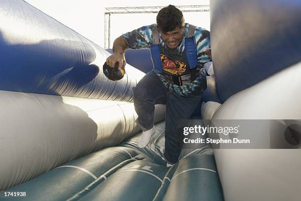 Fan struggles to carry the football while being restrained by a bungee cord harness at the NFL Experience on January 23, 2003 in San Diego,...