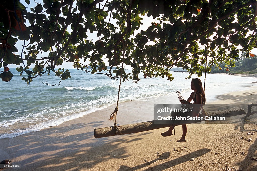 Woman resting on beach swing.