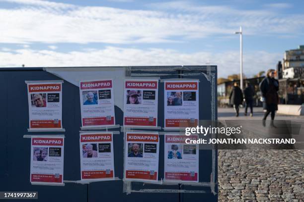 People walk past posters showing recently kidnapped Israelis, following the Hamas attacks on Israel, in Stockholm, Sweden, on October 24, 2023.