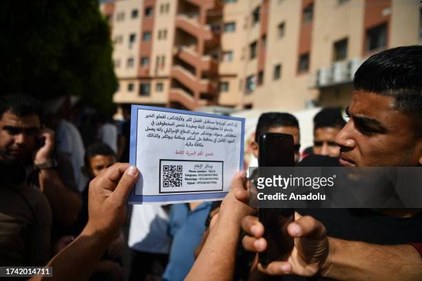 Man holds an air-dropped leaflets from Israeli aircraft, calling on residents to provide information about the hostages held by Hamas in return for...