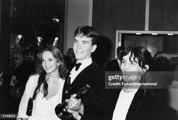 American actor Timothy Hutton holds his Best Supporting Actor Oscar statuette while posing with his girlfriend, actor Diane Lane, and his mother,...