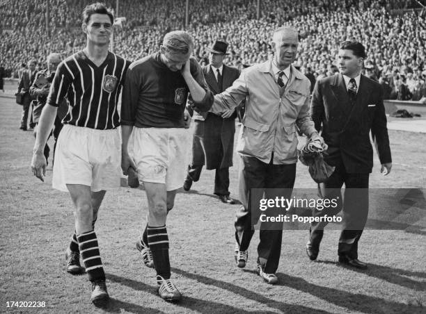 German goalkeeper Bert Trautmann , of Manchester City FC, leaves the field with an injured neck at the end of the FA Cup Final against Birmingham...