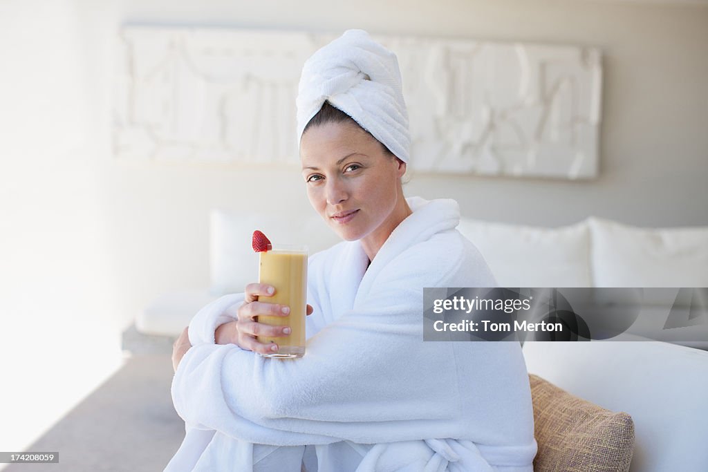 Woman in bathrobe drinking smoothie