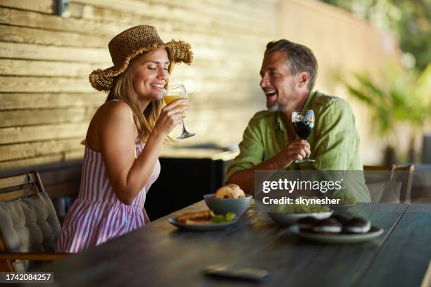 happy couple enjoying in drinks during summer day on a patio. - mid adult couple stock pictures, royalty-free photos & images