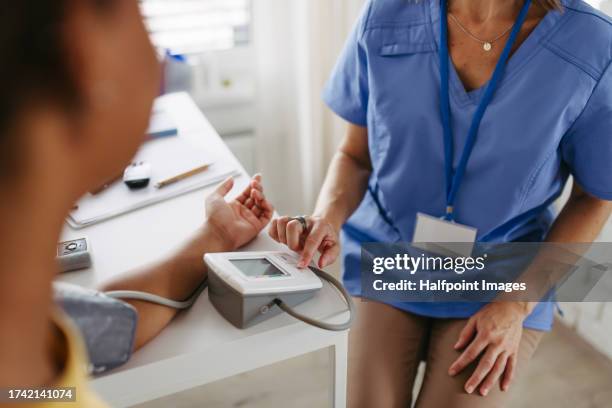 doctor measuring teen patient's blood pressure. - cholesterol stockfoto's en -beelden
